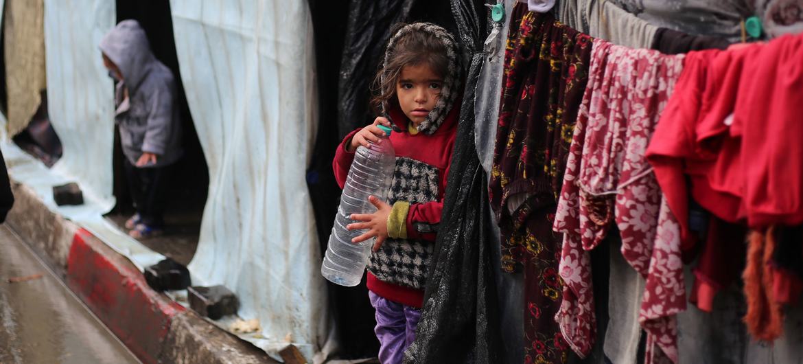 A girl stands in front of her shelter in the city of Rafah.